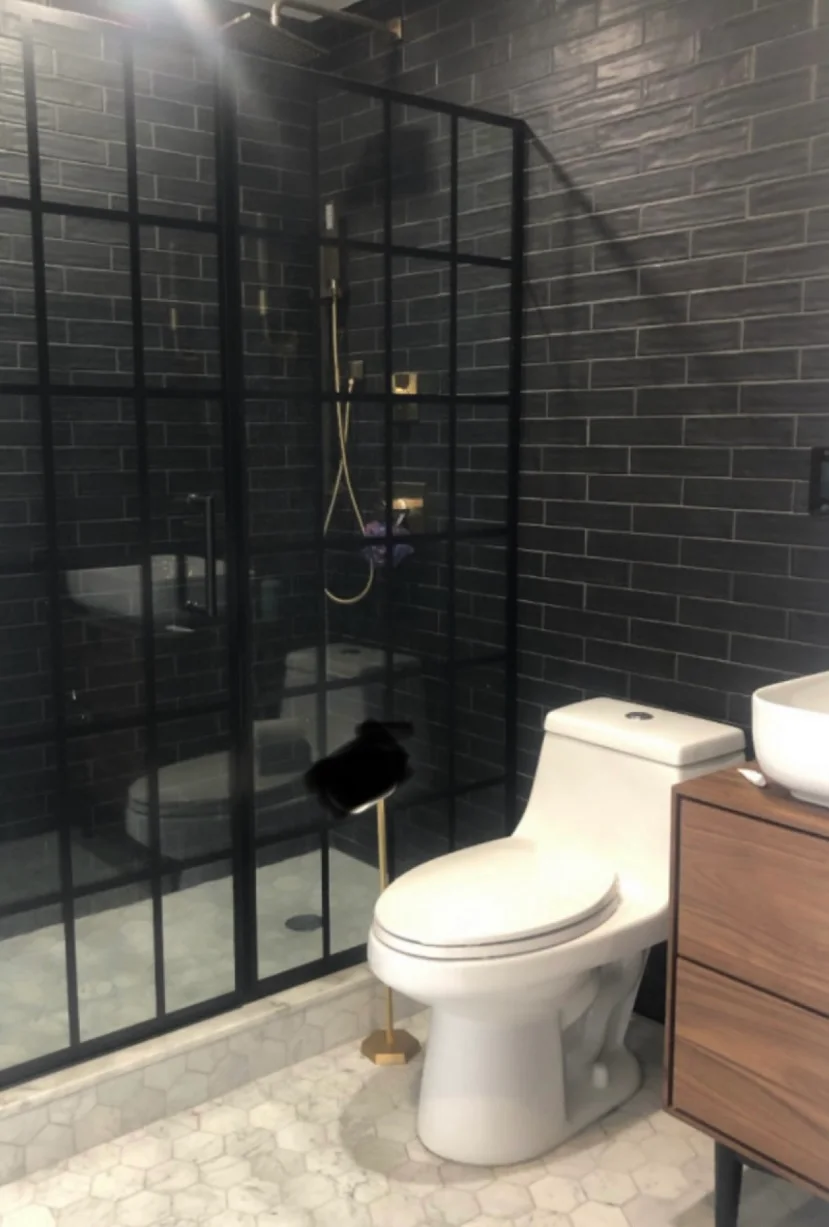 HKB bathroom with dark tile and a black-framed glass shower